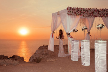 Sunset. bride silhouette. Wedding ceremony arch with flower arra