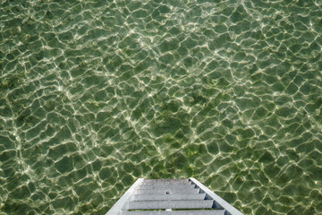 Stegleiter zum Wasser am Bodensee. Wasseroberfläche gekräuselt, Farbe grün