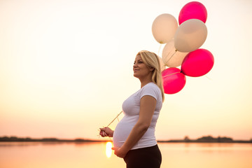 Pregnant woman holding balloons