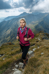 Naklejka na ściany i meble Woman backpacker hiking on a trail