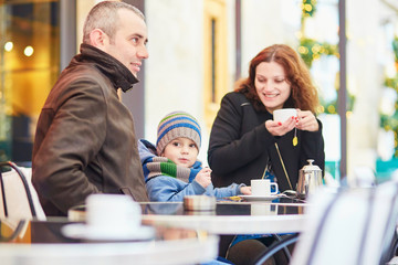 Happy family of three in outdoor cafe