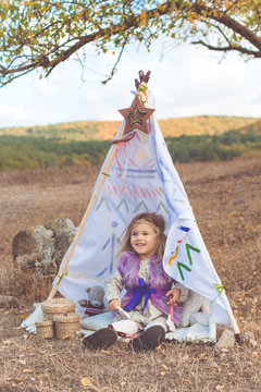 Little girl is sitting in decorative hovel outdoors