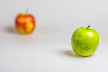 Green apple in the foreground, red apple in the background