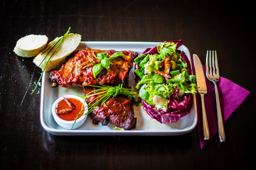 Tableview of spareribs with salad, chili sauce and baguette on w