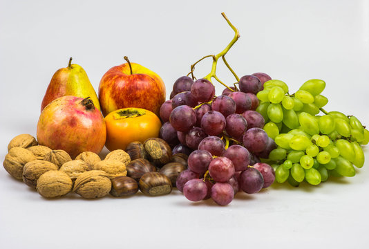 Still life, autumn food on white background - Chestnuts, walnuts, persimmon, peer, apple, pomegranate, grapes