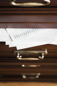 A drawer of wooden commode  full of paper documents. Selective focus