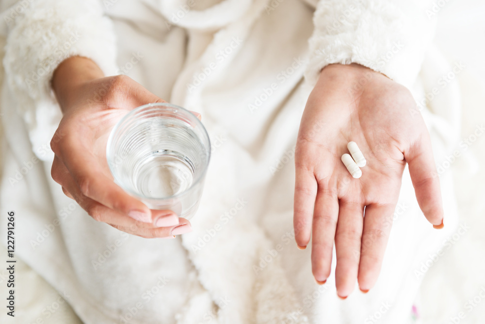 Wall mural Woman holding a glass of water and pills, detail  