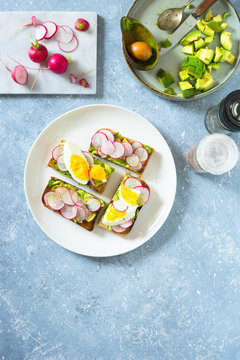 Avocado toast with radishes and boiled egg. Overhead view, copy space.