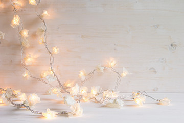 Christmas lights burning  on a white wooden background. Xmas background.
