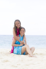 Fototapeta premium Lovely Mother and Girl Sitting on the Beach