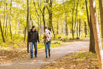 Fototapeta premium Happy young family walking down the road outside in autumn nature.
