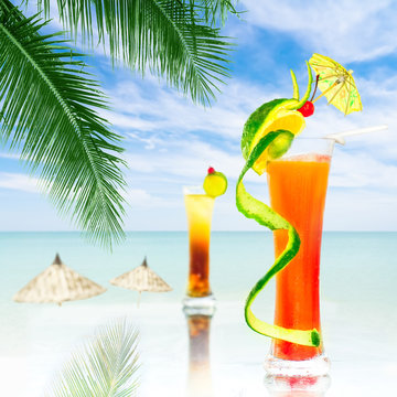Two alcohol cocktails with fruit decoration served at bar on tropical ocean beach