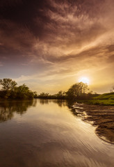 Fototapeta na wymiar Spectacular sunset reflection in a wild river, in summer