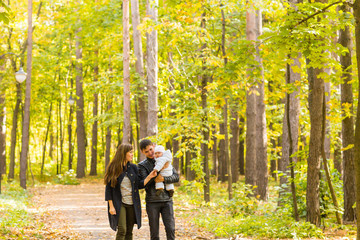 Fototapeta premium Happy young family walking down the road outside in autumn nature.