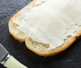 Sandwich, bread with butter and a knife on stone background