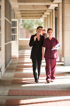 Female Doctor And Nurse Walking Down Corridor