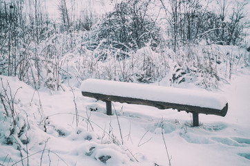 Winter landscape with wooden bench covered with snow, northern seasonal hipster background.