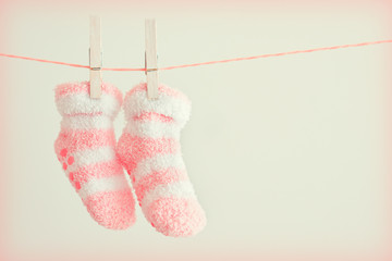 Pink baby socks on a grey background with copy space