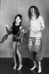 Portrait of men and women have dreadlocks, hippie style. Modern young couple is wearing trendy clothes, on a gray background. 