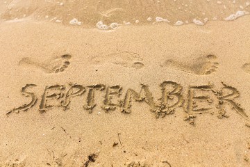 Inscription on wet sand september
beach.