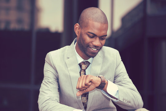 Handsome businessman looking at his watch sitting outdoors