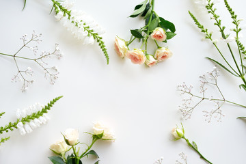 Assorted roses heads on white background. Flowers and leaves scattered on a table, overhead view...