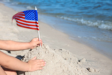 Child building sand castle with American flag on beach