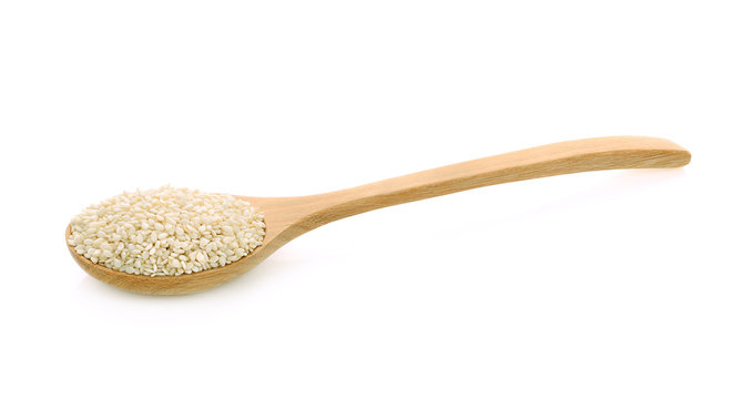 white sesame seeds in wooden spoon isolated on a white
