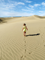 Fototapeta na wymiar little girl walk and leaves footprints on desert sand dune