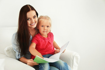 Mother with daughter reading book on chair