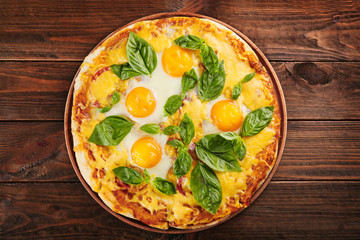 Margarita pizza with basil leaves and egg on wooden background