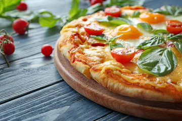Margarita pizza with basil leaves and egg on wooden table closeup
