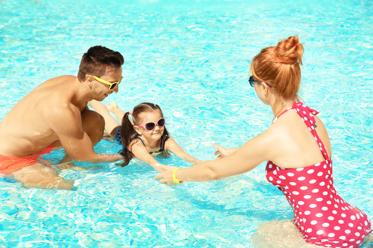 Parents teaching little daughter to swim