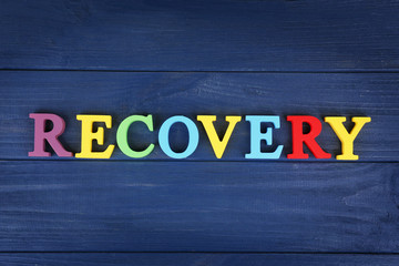 Word RECOVERY made of colourful letters on blue wooden background
