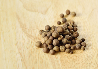 Black round pepper on wooden background