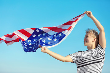 Young woman holding American flag on blue sky background