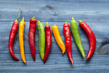 Color cayenne chilli peppers on blue wooden table