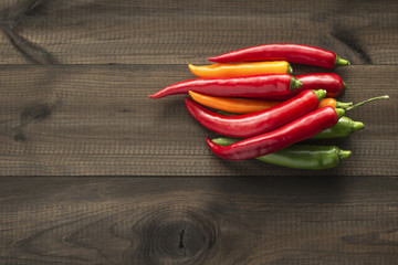 Colorful cayenne chili peppers on wooden table.