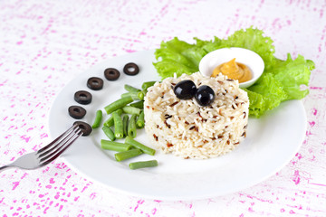 Garnish - Bowl of cooked mixed wild Rice. Plate Served with salad and green bean vegetable.