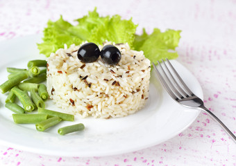 Garnish - Bowl of cooked mixed wild Rice. Plate Served with salad and green bean vegetable.