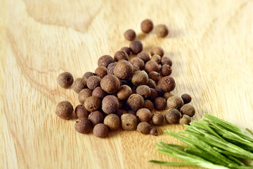 Black pepper on wooden background and green rosemary