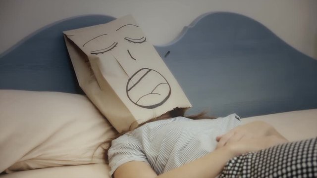 A breadbag face, alone in the bed, having a disturbed sleep, snoring. Close-up shot.
