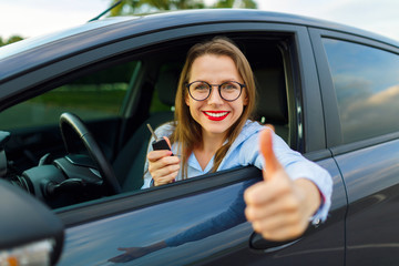 Fototapeta na wymiar Young happy woman sitting in a car with thumb up
