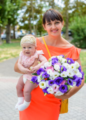 Mother holding a cute baby girl and bouquet