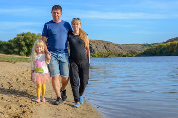 Pretty little girl with her parents at a lake