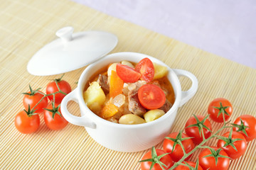 A bowl of healthy potato soup with carrot, tomatoes and meat