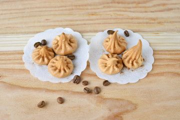 Vanilla meringue cookies on wooden background with copy space. Cakes with white ribbon and coffee.