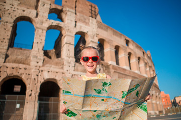 Adorable little active girl with map in front of Colosseum in Rome, Italy. Kid spending childhood in Europe