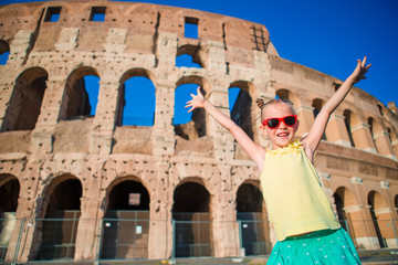 Adorable little active girl having fun in front of Colosseum in Rome, Italy. Kid spending childhood...