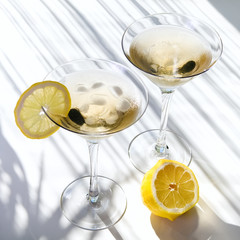 Top view of martini alcohol cocktail with yellow lemon on white with shadows